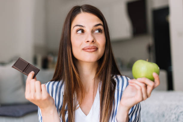 istock woman choosing between chocolate and apple 1183058240