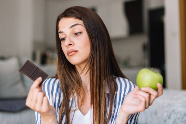 istock woman choosing between chocolate and apple 1183058330