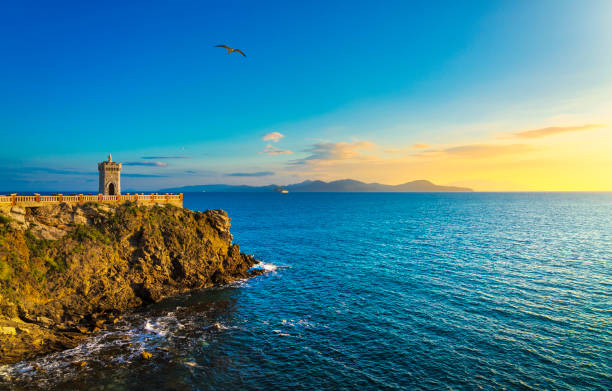 Sunset view of Piombino piazza bovio lighthouse and Elba Island. Tuscany Italy Sunset view of Piombino piazza bovio lighthouse and Elba Island. Maremma Tuscany Italy livorno stock pictures, royalty-free photos & images