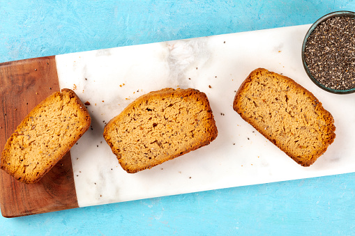 A close-up of a chia seed cake, shot from above on a marble cutting board and a blue background with copy space, healthy vegan baking