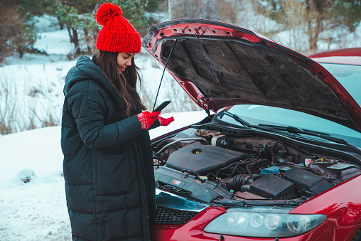mujer pidiendo ayuda con el coche descompuesto en la carretera de invierno se detuvo en la carretera photo
