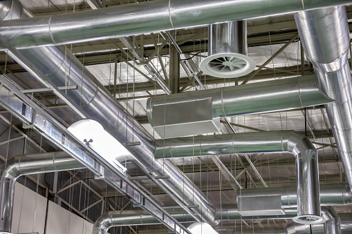 industrial ventilation in a brand new warehouse, tubing installed for the air condition, the shiny tubing is suspended on the ceiling