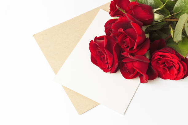 istock Bouquet of red roses and an envelope with a note on a white back 1183064463