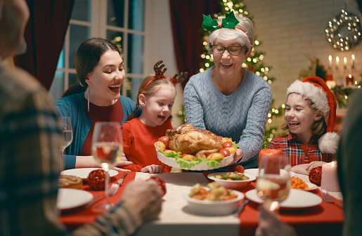 Merry Christmas! Happy family are having dinner at home. Celebration holiday and togetherness near tree.