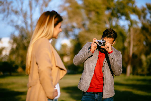 istock Young man taking a photo of his girlfriend in a park using camera 1183070580