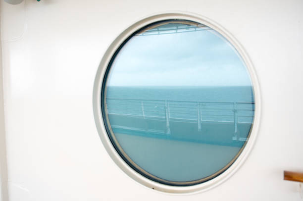 Sea and sky reflecting in round window on nautical vessal at sea.