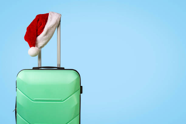 istock Plastic suitcase and Santa Claus hat on blue background. Concept 1183074477
