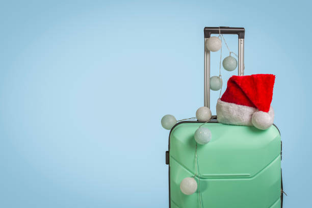 istock Plastic suitcase, Santa Claus cap and garland on a blue backgrou 1183074558
