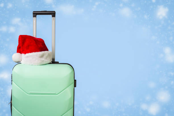 istock Plastic suitcase, Santa Claus hat on blue background with snow. 1183075209