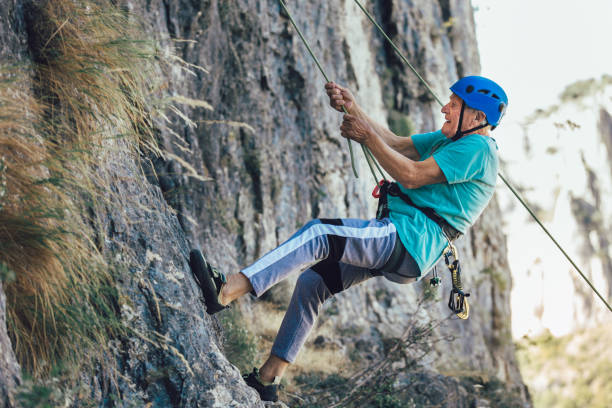 senior mann mit einem seil klettern auf den felsen. - conquering adversity wilderness area aspirations achievement stock-fotos und bilder