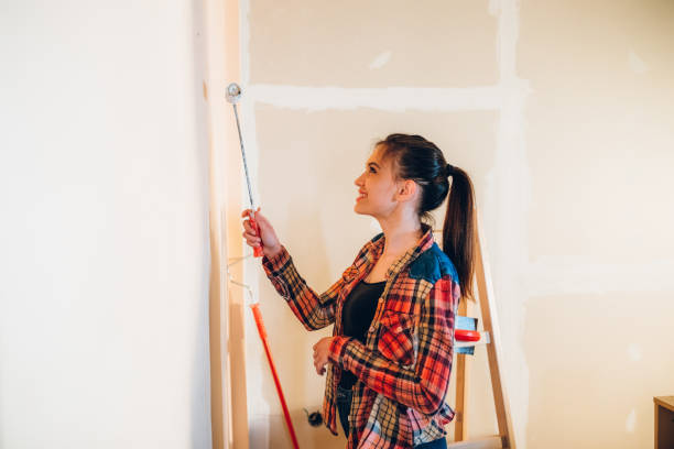 istock Young woman painting wall 1183076645