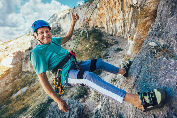 senior mann mit einem seil klettern auf den felsen. - conquering adversity wilderness area aspirations achievement stock-fotos und bilder