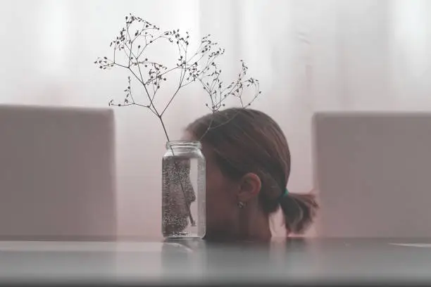 Photo of The girl's face reflected in glass jar.