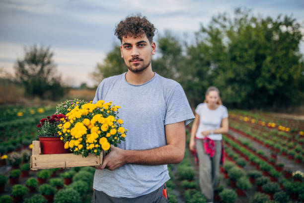 istock Man holding flower pots on flower farm 1183080830
