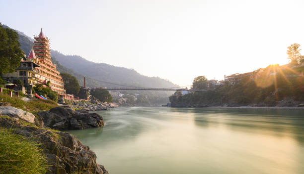 vue imprenable sur le remblai de la rivière ganga avec le pont lakshman jhula et le temple de ta manzil (trimbakeshwar) lors d'un beau coucher de soleil. rishikesh, uttarakhand, inde. - front view photos photos et images de collection