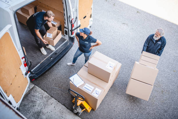 istock Uniformed Team of Delivery Drivers Loading Packages on Van 1183087737