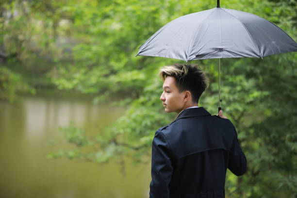 istock Spring rainy weather and a young man with an umbrella 1183087744