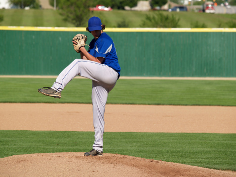 Baseball pitcher, match and athlete throw or pitch ball in a game or training with a softball team. Sports, fitness and professional man or person in a competition with teamwork in a stadium