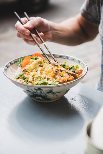 istock Man eating vietnamese noodle curry with duck with bamboo chopsticks 1183093115