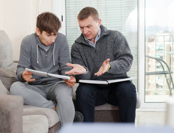 istock Father and teen son solve school assignment together 1183095117