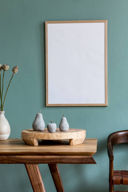 istock Stylish and minimalistic dining room interior with mock up poster frame, wooden table, flowers in vase, fruit tray and elegant accessories. Eucalyptus color. Ready to use. Template. Modern home decor. 1183095251