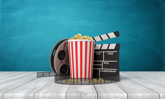 3d rendering of pop corn bucket, film reel, and clapperboard standing on wooden floor near blue wall. Cinematography. Release of new movies. Box office hits.