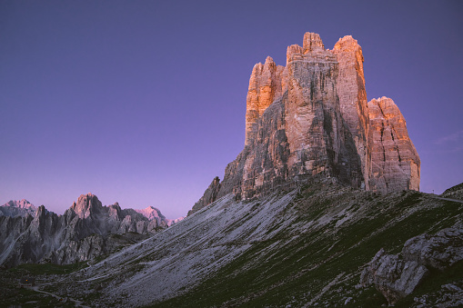 Italian alps - Drei Zinnen (Tre Cime di Lavaredo). First sun rays touching mountains peaks. Mountains in the early dawn.