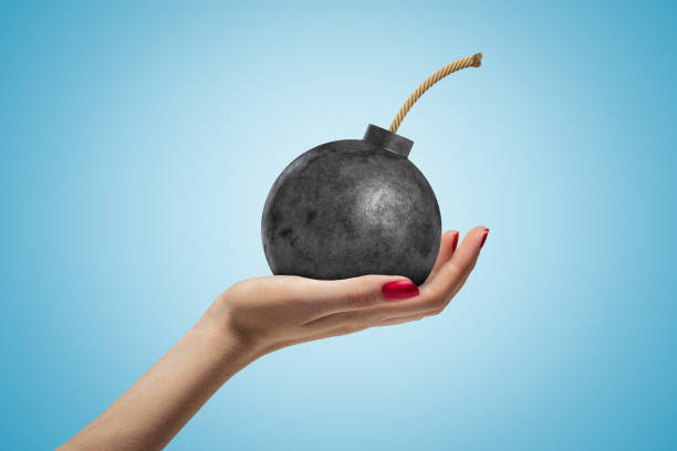 istock Female hand holding ball bomb with fuse on blue background 1183102010