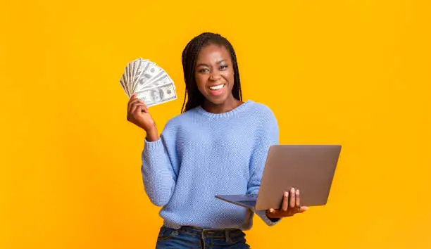 Photo of African american young woman making money from internet, using laptop