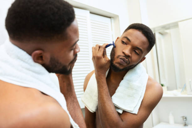 istock Black millennial guy shaving his beard in bathroom 1183103233