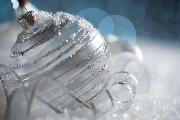 Silver Christmas baubles on snow with a silver background