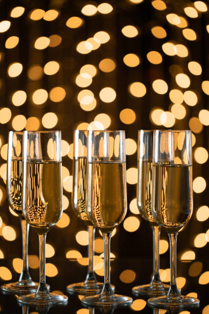 istock Three Champagne glasses with sparklings, yellow lights in the background 1183103756