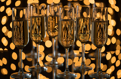 Three Champagne glasses with sparklings, yellow lights in the background