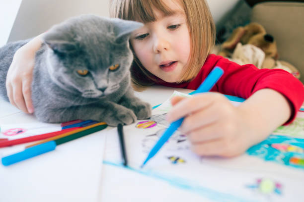 istock Child with cat drawing at home 1183104199