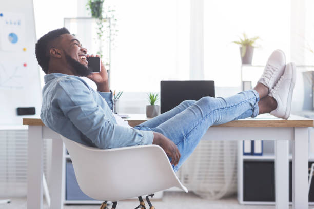 istock Employee putting his legs on table and talking on phone 1183105366