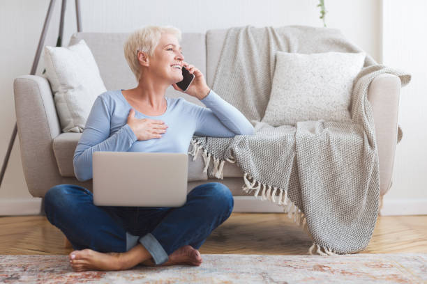 Joyful elderly business woman talking with clients, working at home