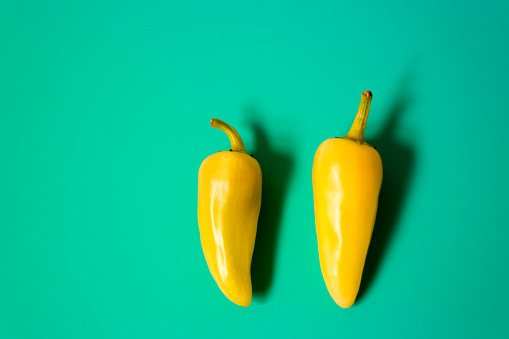 Two Yellow NM Chili Peppers on Green Background. Shot in Santa Fe, NM.