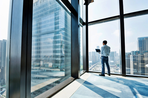 Businessman standing by the window and using laptop