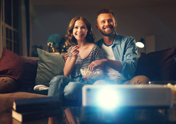 istock Family couple watching television projector at home on sofa 1183108336