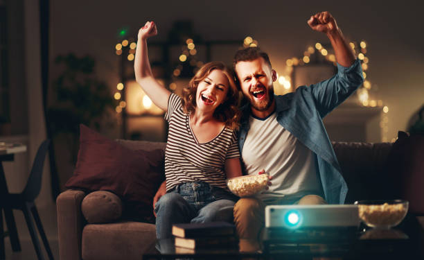 istock Family couple watching television projector at home on sofa 1183109818