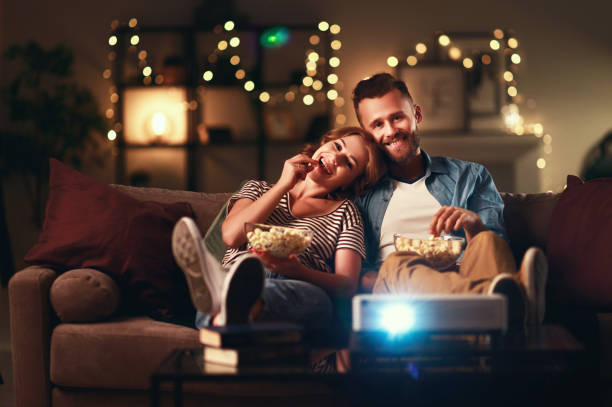Family couple watching television projector at home on sofa