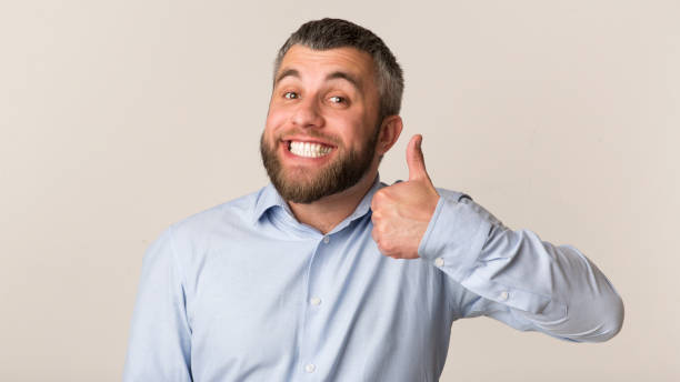 istock Happy bearded man showing thumb up and smiling at studio 1183110870