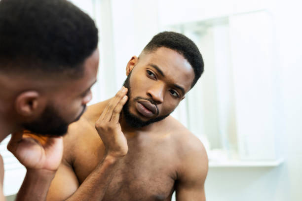 istock Worried millennial african guy checking his face, looking at mirror 1183114707