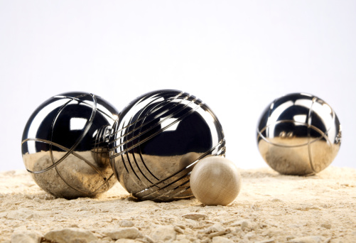 Two boules balls lie next to the target ball, another ball is in the background.