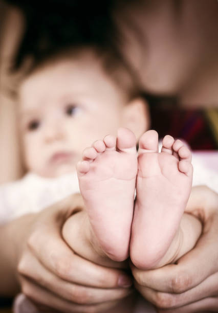 Newborn baby's feet are still very small. The baby's feet are held by the mother with great affection