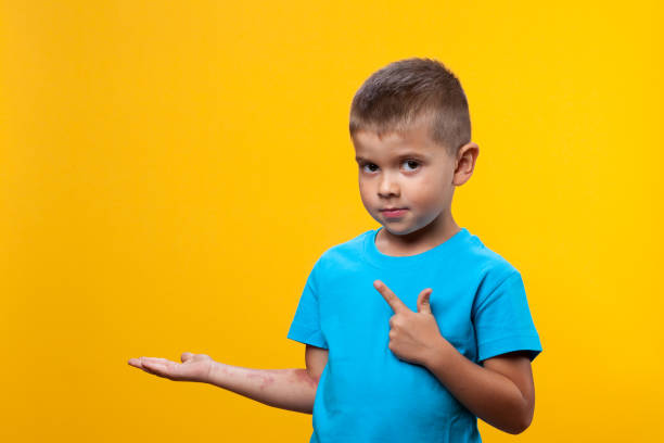 dziecko w wieku 5 lat wyciąga rękę, pokazuje coś i patrzy na żółte tło. - surprise child 4 5 years little boys zdjęcia i obrazy z banku zdjęć