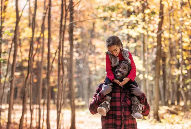 Mixed race family doing piggyback, in the forest, during autumn, Quebec, Canada