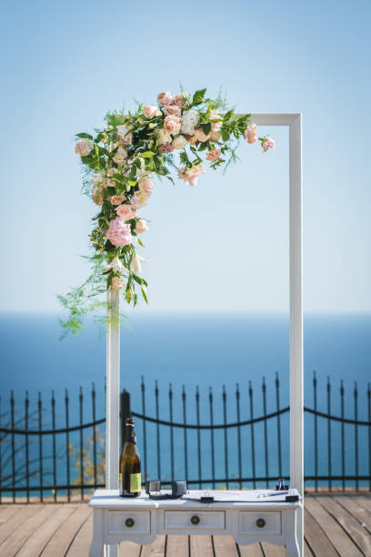 Wedding arch decorated with white and pink roses and green leaves. Outdoor wedding ceremony. Sea background stock photo