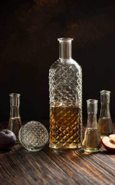 rakia lub rakija tradycyjna bałkańska brandy owocowa. śliwkowa brandy slivovica w szklance, która nazywa się cokanj i butelka na drewnianym stole i ciemnym tle. pionowy. obszar kopiowania - vodka hard liquor bottle palinka zdjęcia i obrazy z banku zdjęć