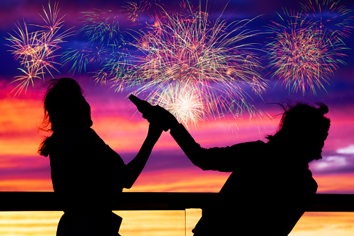 shadow of women celebrate with colorful fireworks display on sunset sky, celebration concept